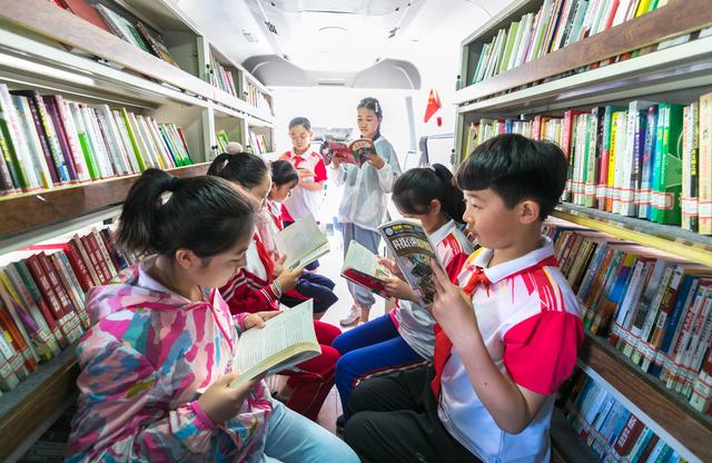 呼和浩特市玉泉区恒昌店巷小学的孩子们在"流动图书车"内翻阅图书