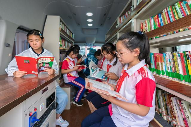 呼和浩特市玉泉区恒昌店巷小学的孩子们在"流动图书车"内翻阅图书