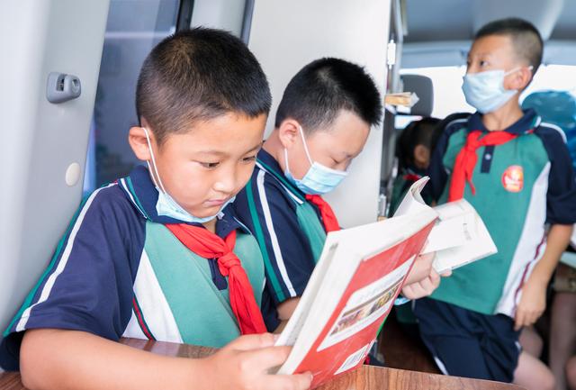 呼和浩特市玉泉区恒昌店巷小学的孩子们在"流动图书车"内翻阅图书