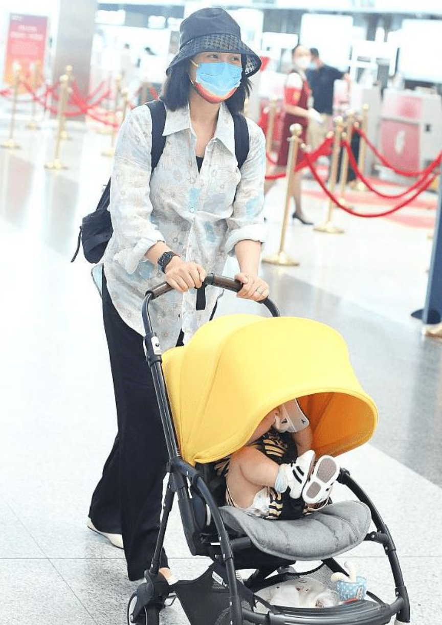 朱丹带一双儿女赶飞机，不时低头看孩子，却不见丈夫周一围的身影